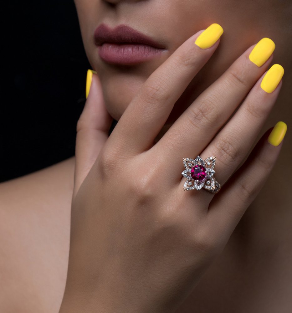 woman hand with flower shaped diamond ring with white burgundy stone